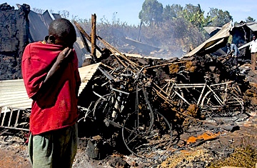A man grieves at the site of the church burned after the elections of 2008, with over fifty Kikuyu women and children burned to death inside.