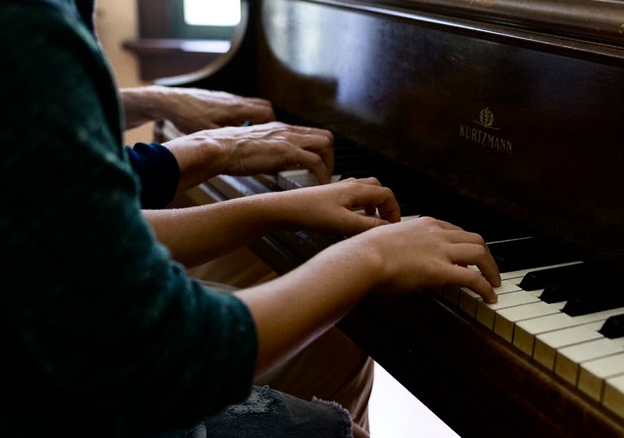 A young piano player gets help at a recital.