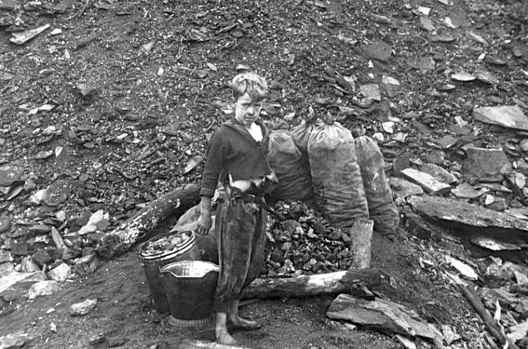 Young boy scavenges in slag heap for enough coal to keep his family warm for a few days.