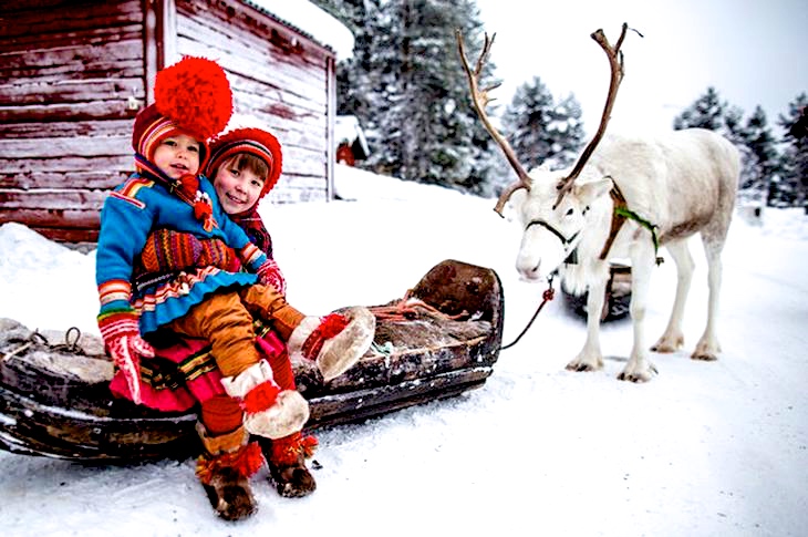 Sami children on their reindeer-drawn sled. Their shoes are of traditional reindeer hide.