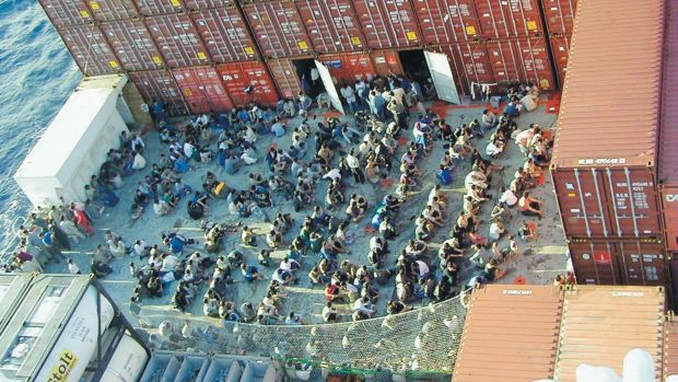 Refugees sit on deck of the Tampa,surrounded by shipping containers.